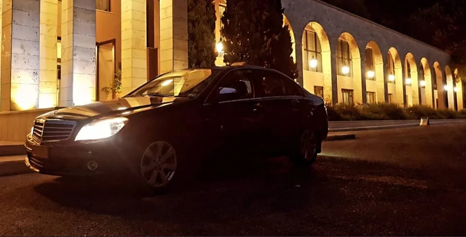 The Mercedes C-Class at night in front of lit arches